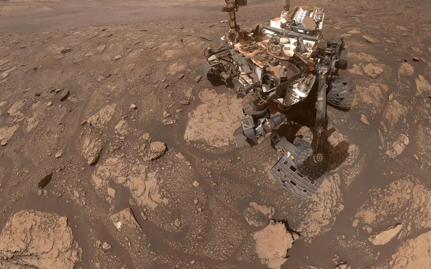 Curiosity rover beside a drilled rock site on Mars